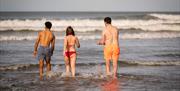 Group walking into the water enjoying the Mussenden Unwind experience