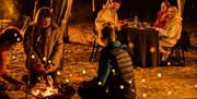 Group on the beach at night-time enjoying refreshments as part of the Mussenden Unwind experience