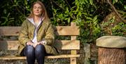 Lady relaxing on a bench with her eyes closed enjoying the Journey into Stillness experience