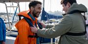 Two men fixing their lifejackets as part of the Giant Shipwrecks of the North Coast experience