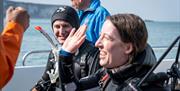 Group on a boat in scuba diving gear high-fiving each other as part of a scuba diving experience with Aquaholics