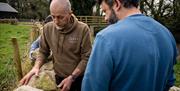 Instructor Mark moving large stones in front of a guest as part of the Mourne Dry Stone Wall Building experience