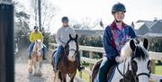 Group on horseback leaving the stables as part of the Saddle Up by the Sea experience with Crindle Stables