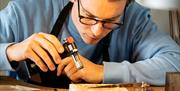 Man making jewellery holding a blowtorch as part of the jewellery making workshop with Gobbins Crafts in Islandmagee