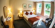 Double bedroom in Rosspark Hotel with white bedding and orange cushions / runner plus dark grey carpet.