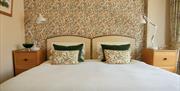 Image of a bed with patterned wall paper and matching cushions.