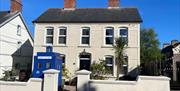 White exterior of Sergeants House with old style blue police box as feature in garden