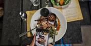 A guest takes a photo of the beautiful meal she is enjoying at the Slemish Supper Club