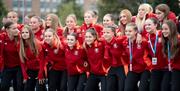 a young women's football team pose for a group photo while wearing red and black athletic uniforms