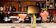 A selection of cocktails sitting on a bench at a bar.