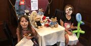 Two little girls sitting at a Teddy Bears Picnic on a train in Whitehead Railway Museum