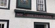 Exterior of the Thatch inn featuring crest above the entrance door