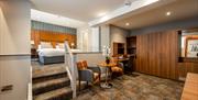 A bedroom with a large wardrobe, a table with two chairs and a few steps up to a raised area with a double bed.