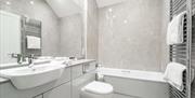 A bathroom with a sink, toilet, bath and towel rack.