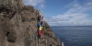 Tour group climbing steps on cliff side