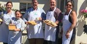 A group of all ages poses with their homemade baked goods outside on a sunny day