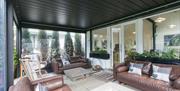 A sunroom with three sofas, two decorative fire pits and two chairs.