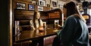 2 females sitting in booth enjoying drinks