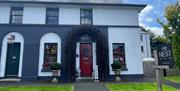 Exterior of the Nest Broughshane with archway over red door and white and grey painted walls