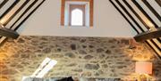 Image shows queen bed with wooden beams and feature stone wall behind bed