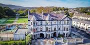 Beautiful exterior of Whistledown Hotel with blue skies, play park to the left and Warrenpoint Band Stand in the distance.