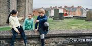 Children sitting on a wall within the village of the Museum