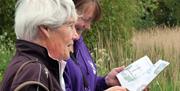 Two women outdoors looking at a Quentin Blake trail map
