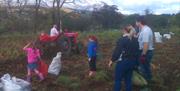 Family gathering potatoes behind a vintage tractor and potato spinner