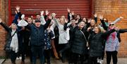 Happy group of guests smiling with their hands in the air of Belfast Food Tour