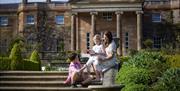 A woman with two children sit on the steps of the South Lawn outside Hillsborough Castle and Gardens