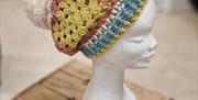 Crochet hat in  multi colours on headstand.