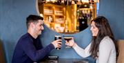 This is a picture of 68 Clooney Restaurant. A male and female are pictured holding up their drink glasses as they smile at each other.