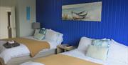 Beach Room with two double beds with blue feature wall.