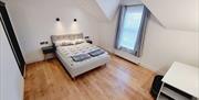 Large master bedroom with bedside tables, a dresser and a window.