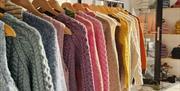 railings in Bramble Green holding a variety of colourful knitted jumpers
