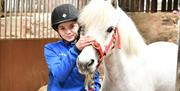 a girl standing with a white hose in the stables