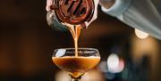 Photo of an espresso martini being poured from the shaker into a glass.