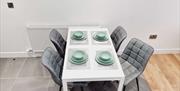 White table with grey chairs and green crockery set.