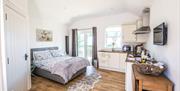 Open plan view, double bed and kitchen area with patio doors leading to outside patio area.
