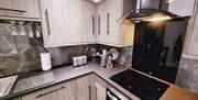 Close up kitchen area with view of oven/hob, toaster and various utensils.