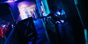 A girl peeking around a corner playing laser tag.