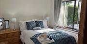 Double bedroom with drawers, a window and folded towels.