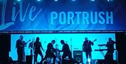 performers on a lit stage - a banner above them reads 'Live Portrush'