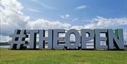 large outdoor signage in Portrush reads '#THEOPEN'