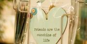 Display of paper and wood hearts, with text printed on reading friends are the sunshine of life, by Paperdove.