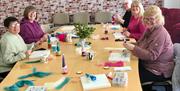 5 middle aged ladies sitting around a large table learning how to needle felt in the Rankin Room of Midtown Makers
