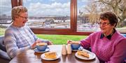 Two visitors enjoying a coffee and traybake in the cafe.