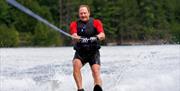 man in wet suit water skiing on lake.