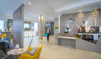 A woman walking through reception while receptionists work.