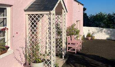 Outside view of the pink cottage with trellis porch